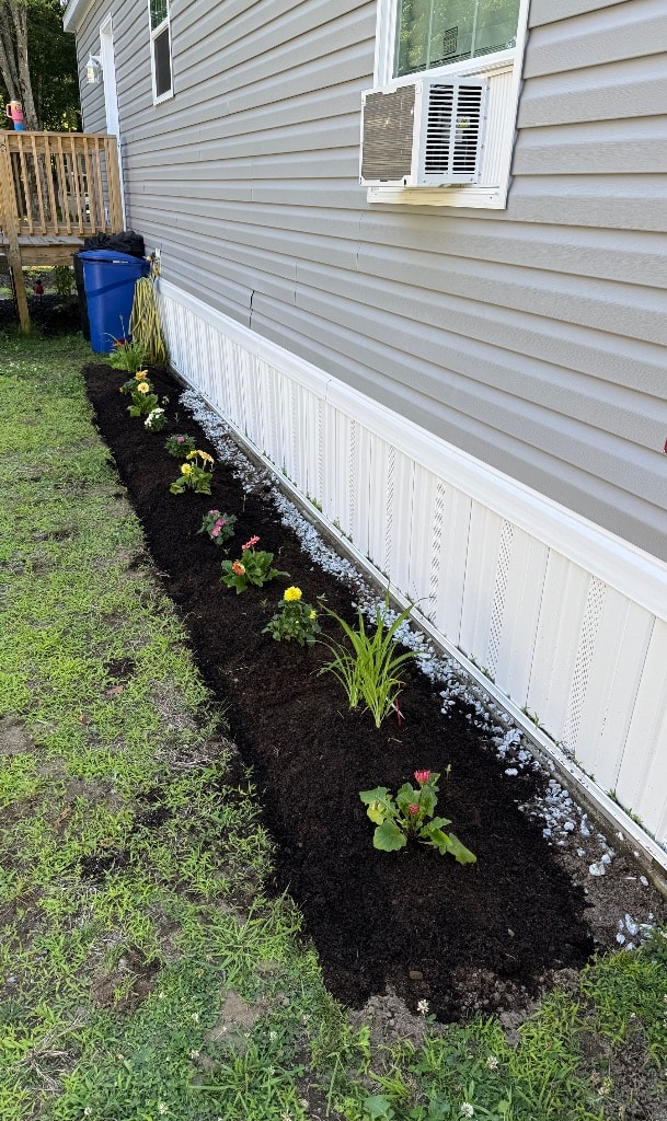 Side Garden 1.0 planted with colorful flowers and white stone edging along the house