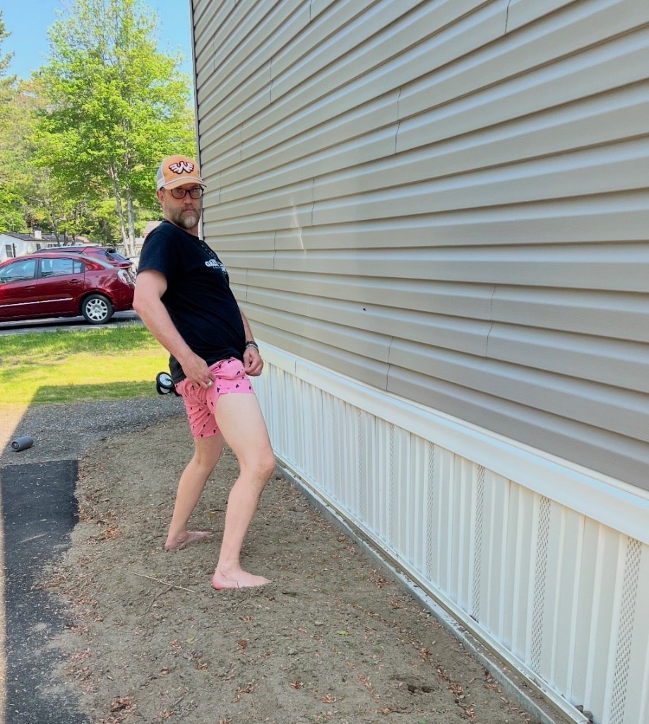 Gardener in pink shorts and bare feet posing beside the house — ready to get to work on the Side Garden